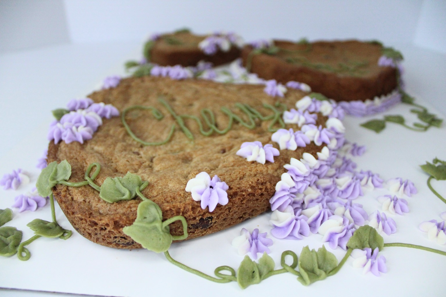 Decorated cookie cake with purple flowers and green vines