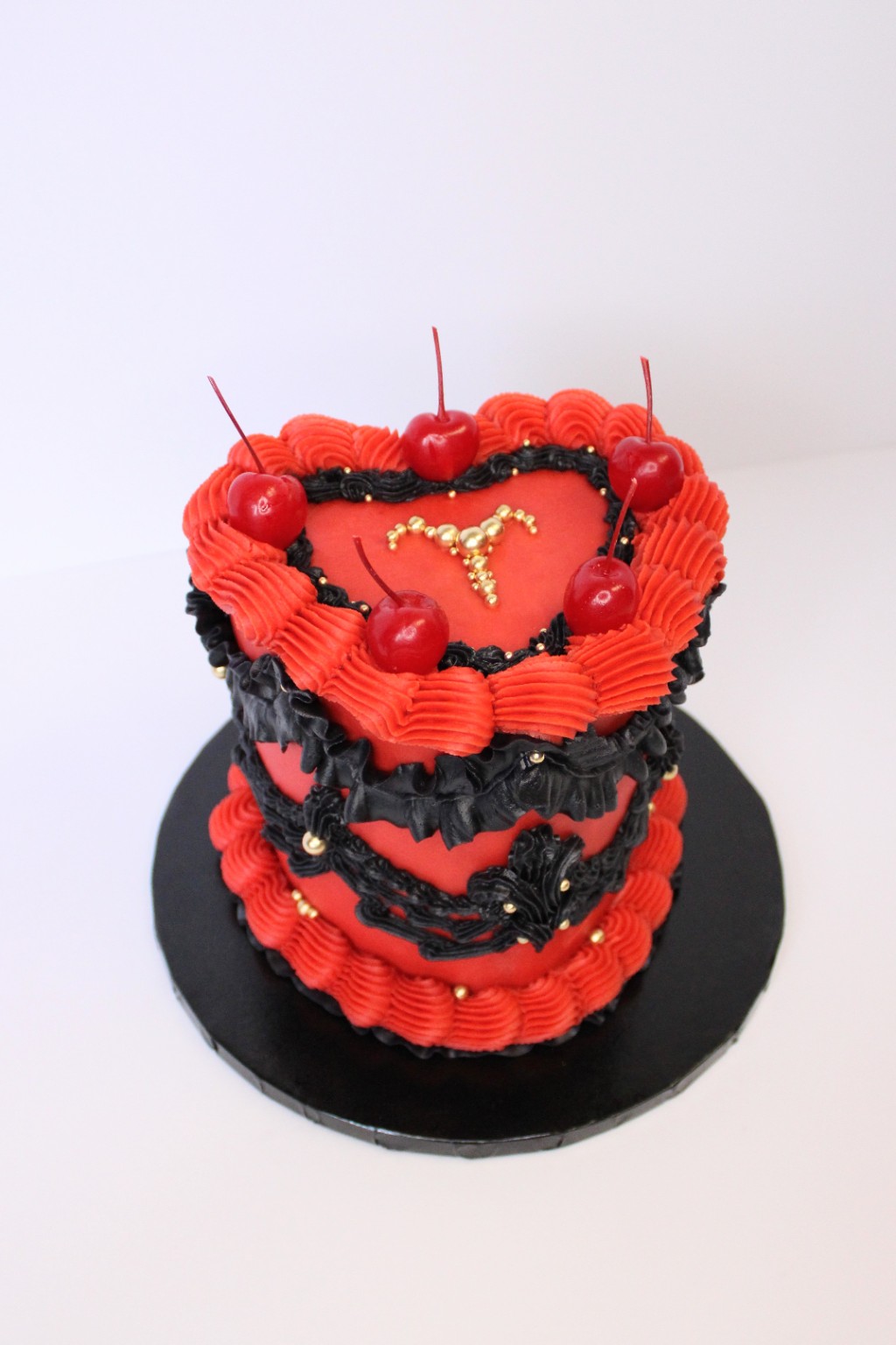 Red and black heart-shaped cake with cherries