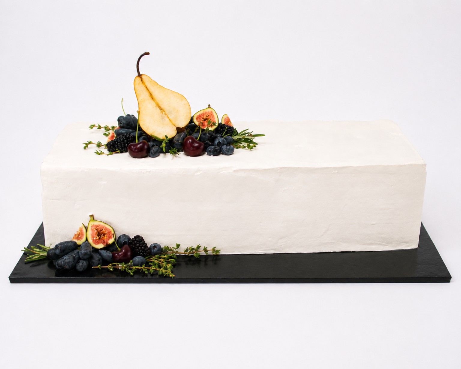 White rectangular custom cake topped with fruit and greenery