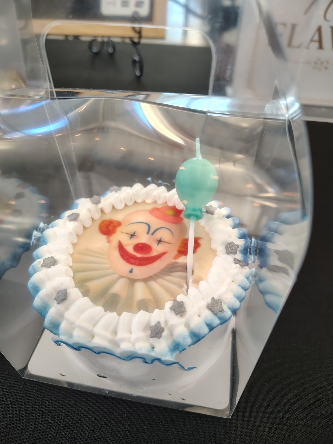 Clown mini cake in blue and white frosting with a red lollipop